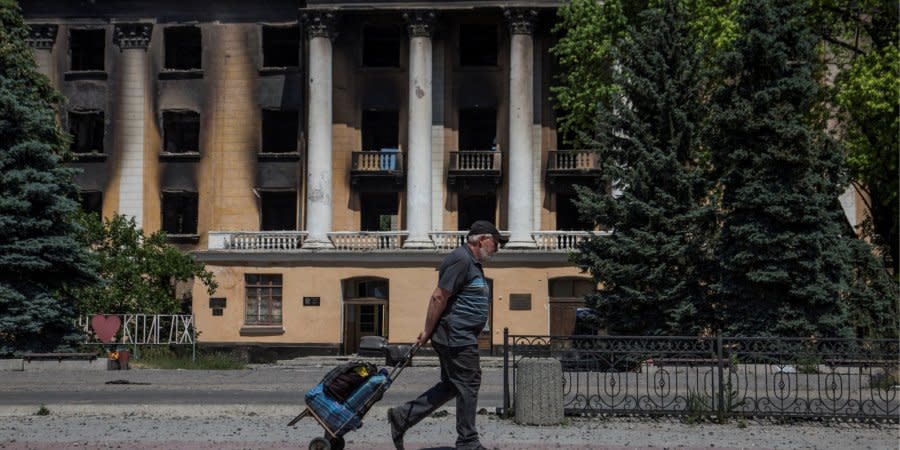 A local resident walks past the building of the State Metallurgical College in Lysychansk, Luhansk Oblast, on June 10, 2022.