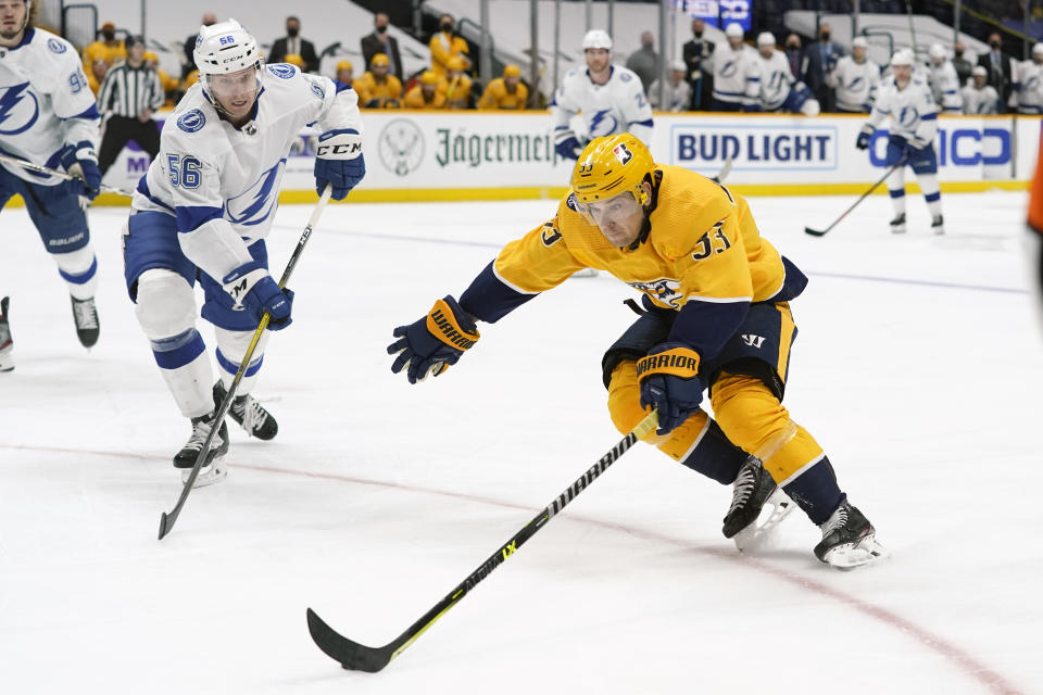 Nashville Predators right wing Viktor Arvidsson (33) moves the puck against Tampa Bay Lightning's Ben Thomas (56) in the second period of an NHL hockey game Saturday, April 10, 2021, in Nashville, Tenn. (AP Photo/Mark Humphrey)