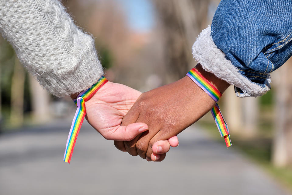 hands of interracial lesbian couple with lgbt rainbow bracelets