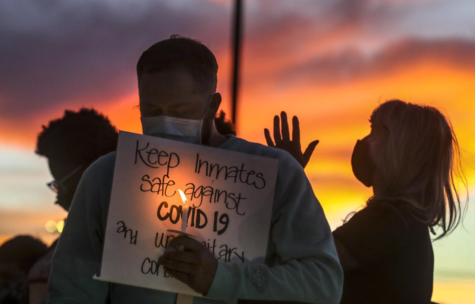 FILE - In this Oct. 13, 2020, file photo, family members of inmates incarcerated in the Utah Department of Corrections' prison system hold candles and say a prayer following a rally outside the Department of Corrections office in Draper, Utah. For 15 months, The Marshall Project and The Associated Press tracked the spread of COVID-19 through prisons nationwide. Prisons were forced to adapt to unusual and deadly circumstances. But now, as new cases are declining and facilities are loosening restrictions, there’s little evidence to suggest enough substantive changes have been made to handle future waves of infection. (Steve Griffin/The Deseret News via AP, File)