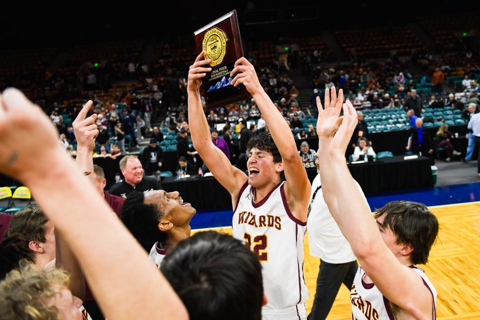 Windsor boys basketball player Johnnie Reed (32) raises a trophy after the Wizards won a quarterfinals game against Longmont during the Colorado 5A state basketball tournament on March 2 at the Denver Coliseum.
