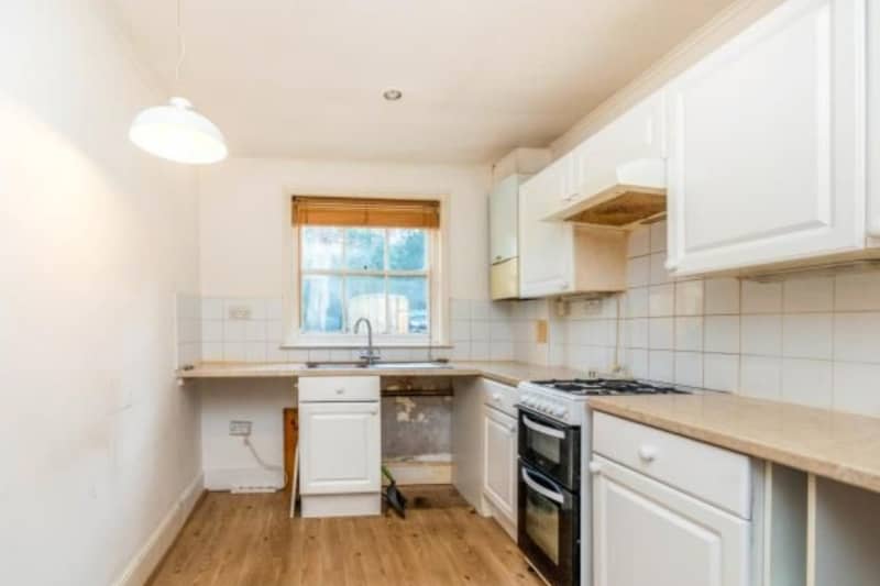 A kitchen going through a renovation with a large window and white walls.