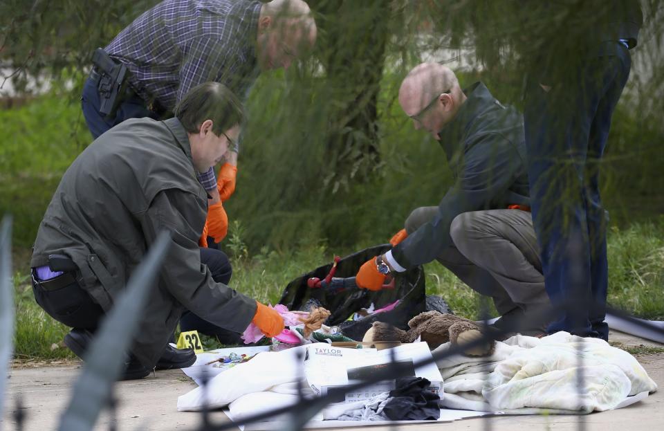 Phoenix Police Department investigators examine toys as they sift through evidence at a home where skeletal remains were found Wednesday, Jan. 29, 2020, in Phoenix. The remains have been found at a house where authorities previously removed at least one child as part of a child abuse investigation in which both parents of that child were in custody, police said Wednesday. (AP Photo/Ross D. Franklin)