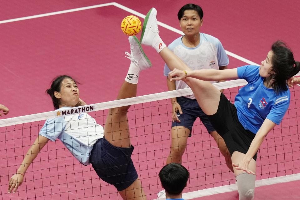 India's Devi Elangbam, left, and Myanmar's Zin Ya Mong compete for the ball during women's sepaktakraw preliminary Group B match at Jinhua Sports Centre at the 19th Asian Games in Jinhua, China, Sunday, Oct. 1, 2023. (AP Photo/Eugene Hoshiko)