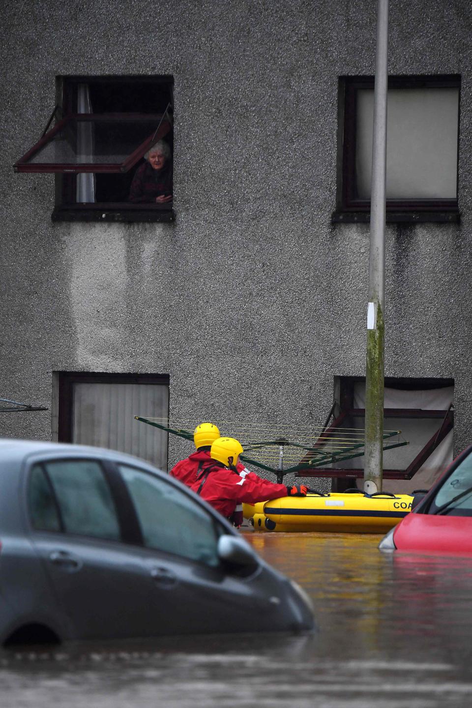Coastguard rescue workers make their way to evacuate a trapped elderly resident in a flooded stret in Brechin (AFP via Getty Images)