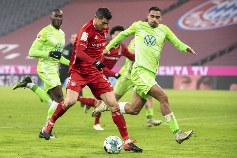 Robert Lewandowski del Bayern Munich va por el balón mientras lo defienden Jerome Roussillon y Maxence Lacroix del Wolfsburgo en el encuentro del miércoles 16 de diciembre del 2020 de la Bundesliga. (Matthias Balk/Pool photo via AP)