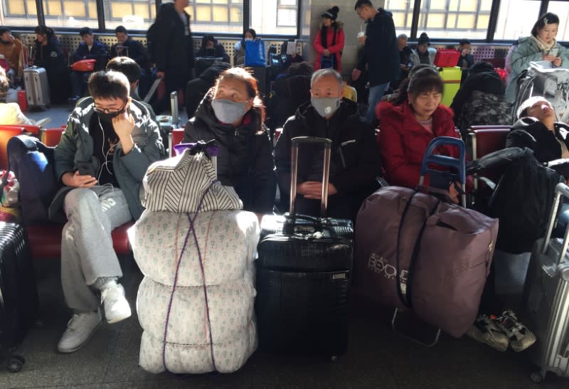 Passengers wearing masks wait to board trains at the Beijing West Railway Station, in Beijing