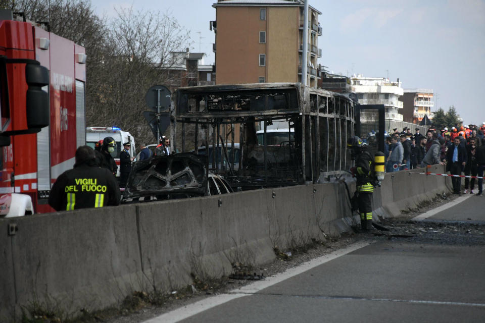 Firefighters stand by the gutted remains of a bus in San Donato Milanese, near Milan, Italy, March 21, 2019. Italian authorities say a bus driver transporting schoolchildren stopped his vehicle on a provincial highway, told the passengers to get off and then doused the interior with gasoline and set it on fire. Italian media reported that the driver, an Italian of Senegalese origin, was immediately apprehended. (Daniele Bennati/ANSA via AP)