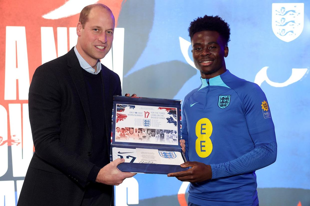 Prince William, Prince of Wales presents an England shirt to Bukayo Saka at St George's Park