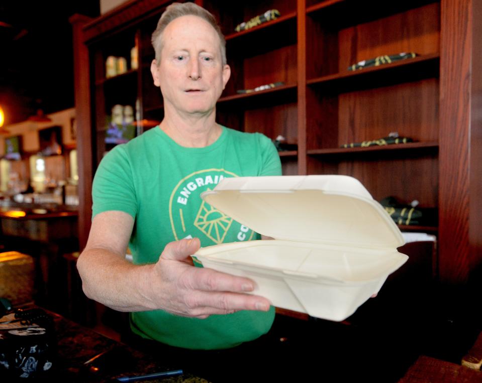 Manager of the Engrained Brewing Company restaurant Steve Margold holds up a to go box made of paper instead of styrofoam Feb. 22, 2023 that the restaurant uses.