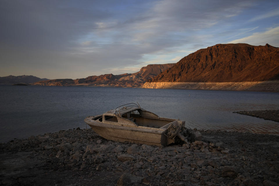 FILE - A formerly sunken boat sits high and dry along the shoreline of Lake Mead at the Lake Mead National Recreation Area, on May 10, 2022, near Boulder City, Nev. Wildfires, floods and soaring temperatures have made climate change real to many Americans. Yet a sizeable number continue to dismiss the scientific consensus that human activity is to blame. That's in part because of a decades-long campaign by fossil fuel companies to muddy the facts and promote fringe explanations. (AP Photo/John Locher, File)