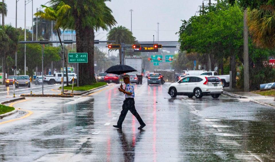 A man crosses 163rd Street in North Miami under heavy rain as a severe weather alert was issued by the National Weather Service on March 22, 2024.