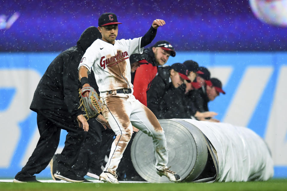 Cleveland Guardians' Steven Kwan avoids the grounds crew rolling out a tarp during a rain delay in the fifth inning of the team's baseball game against the Texas Rangers, Wednesday, June 8, 2022, in Cleveland. (AP Photo/Nick Cammett)