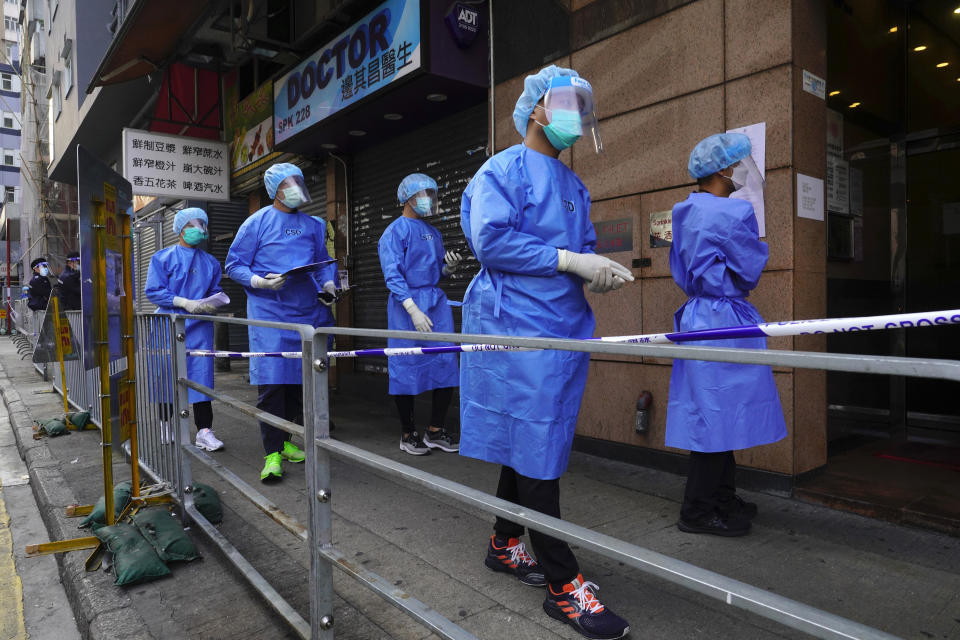 Government investigators wearing protective suits gather in the Yau Ma Tei area in Hong Kong, Saturday, Jan. 23, 2021. Thousands of Hong Kong residents will be locked down in an unprecedented move by the government to contain a worsening outbreak in the city, authorities said Saturday. (AP Photo/Vincent Yu)