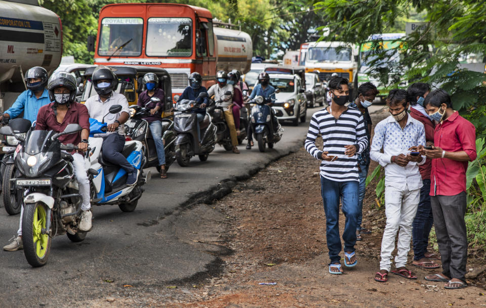 Commuters wearing masks wait at a traffic intersection in Kochi, Kerala state, India, Monday, Sept.28, 2020. India's confirmed coronavirus tally has crossed 6 million cases, only second behind the United States, as the south Asian country continues to battle the worst COVID-19 outbreak in the world. (AP Photo/R S Iyer)