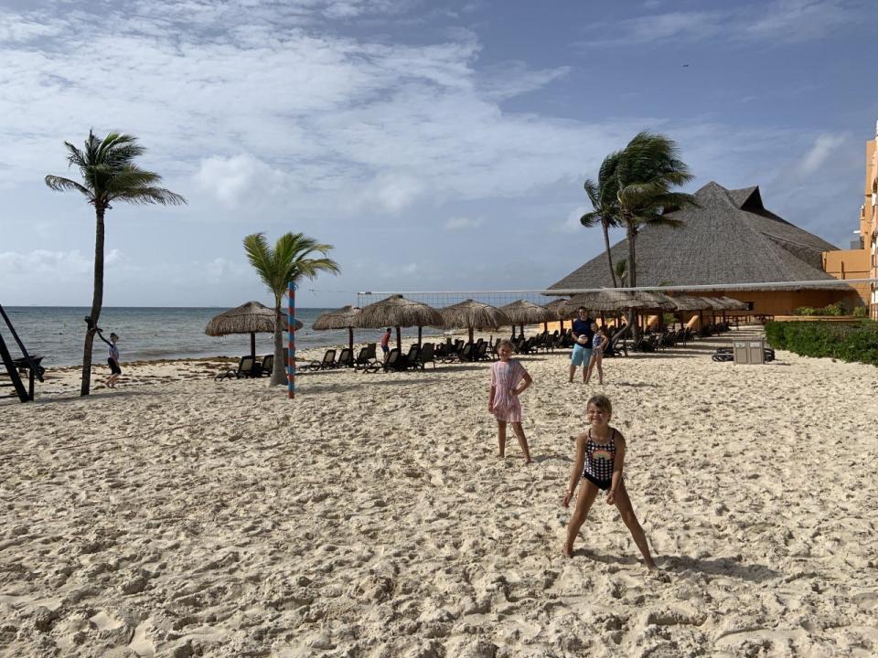 Girls on a tropical beach playing volleyball.