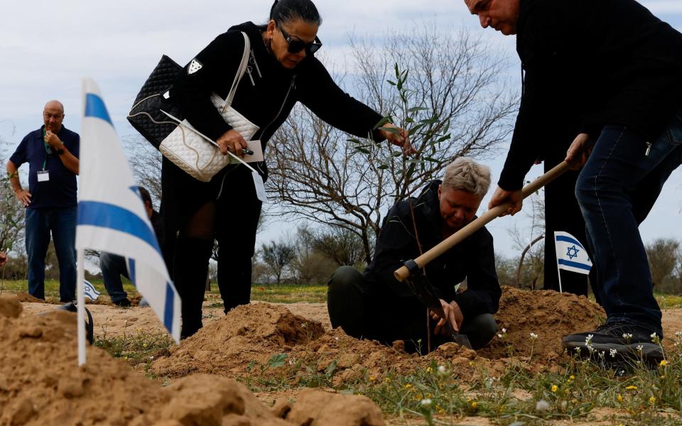 Family members and relatives plant trees in the memory of people who were killed and kidnapped during the October 7 attack