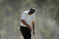 Jason Day, of Australia, shields himself from blowing sand on the 18th hole during second round at the Masters golf tournament at Augusta National Golf Club Friday, April 12, 2024, in Augusta, Ga. (AP Photo/Ashley Landis)