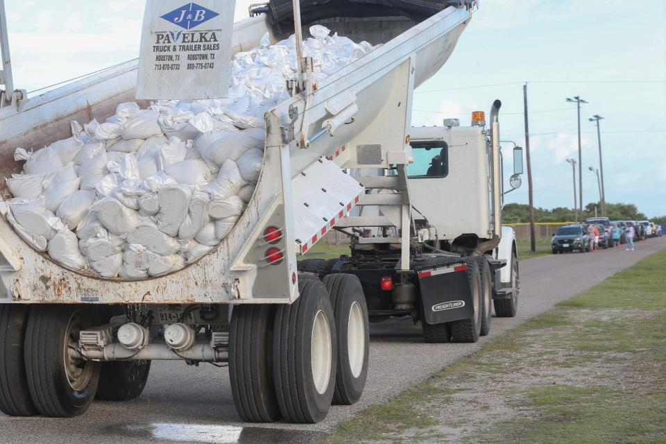 A dump truck starts to release sandbags while residents wait in line at Waldron Field Saturday, June 22, 2024.