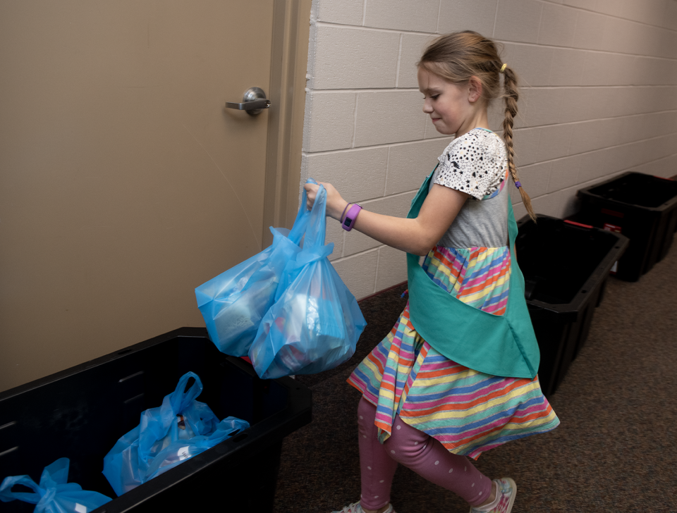 Alyssa Boehlke, 10, with Girl Scout Troop 90110, takes completed Raven Packs to bin for distribution during a volunteer event April 27 at Portage Community Chapel.