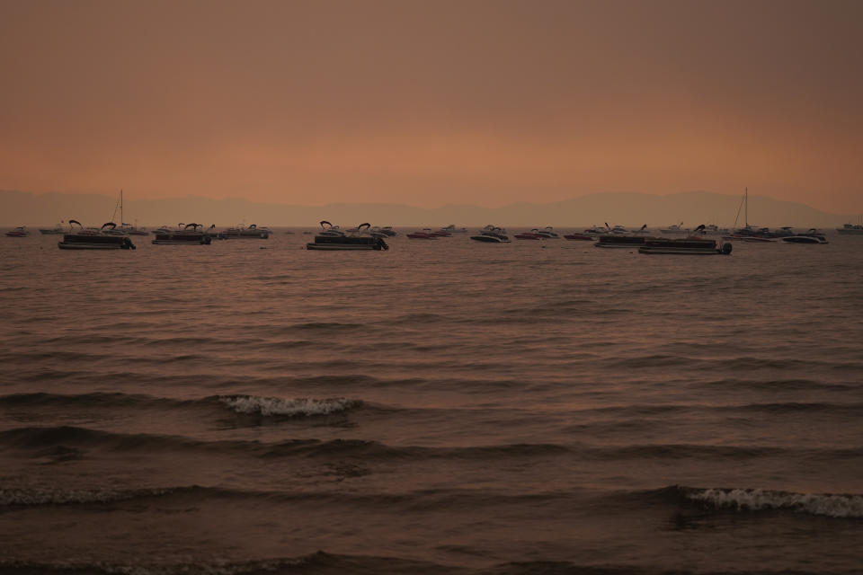 FILE - In this Aug. 31, 2021 file photo boats float in the water away from a dock in South Lake Tahoe, Calif., as the Caldor Fire approaches Lake Tahoe. With wildfire no longer threatening Lake Tahoe, residents, tourists and scientists drawn to its clean alpine air, clear blue waters and fragrant pine trees now wonder about the long-term effects that will remain after wildfire season ends. (AP Photo/Jae C. Hong,File)