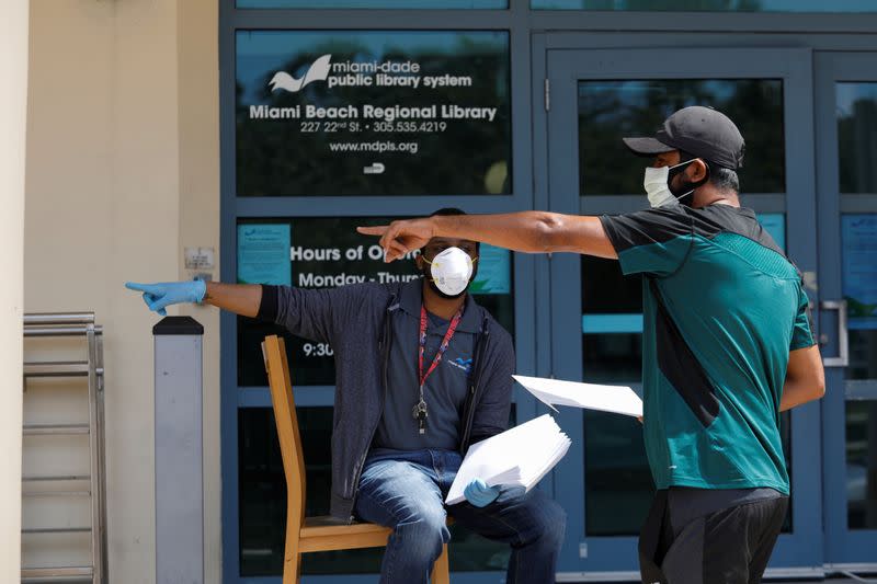 A man speaks with a library worker after receiving an unemployment form, as the outbreak of coronavirus disease (COVID-19) continues, in Miami Beach