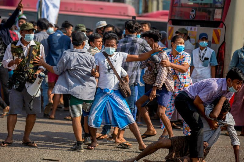 A military supporter points a sharp object as he confronts pro-democracy protesters during a military support rally in Yangon