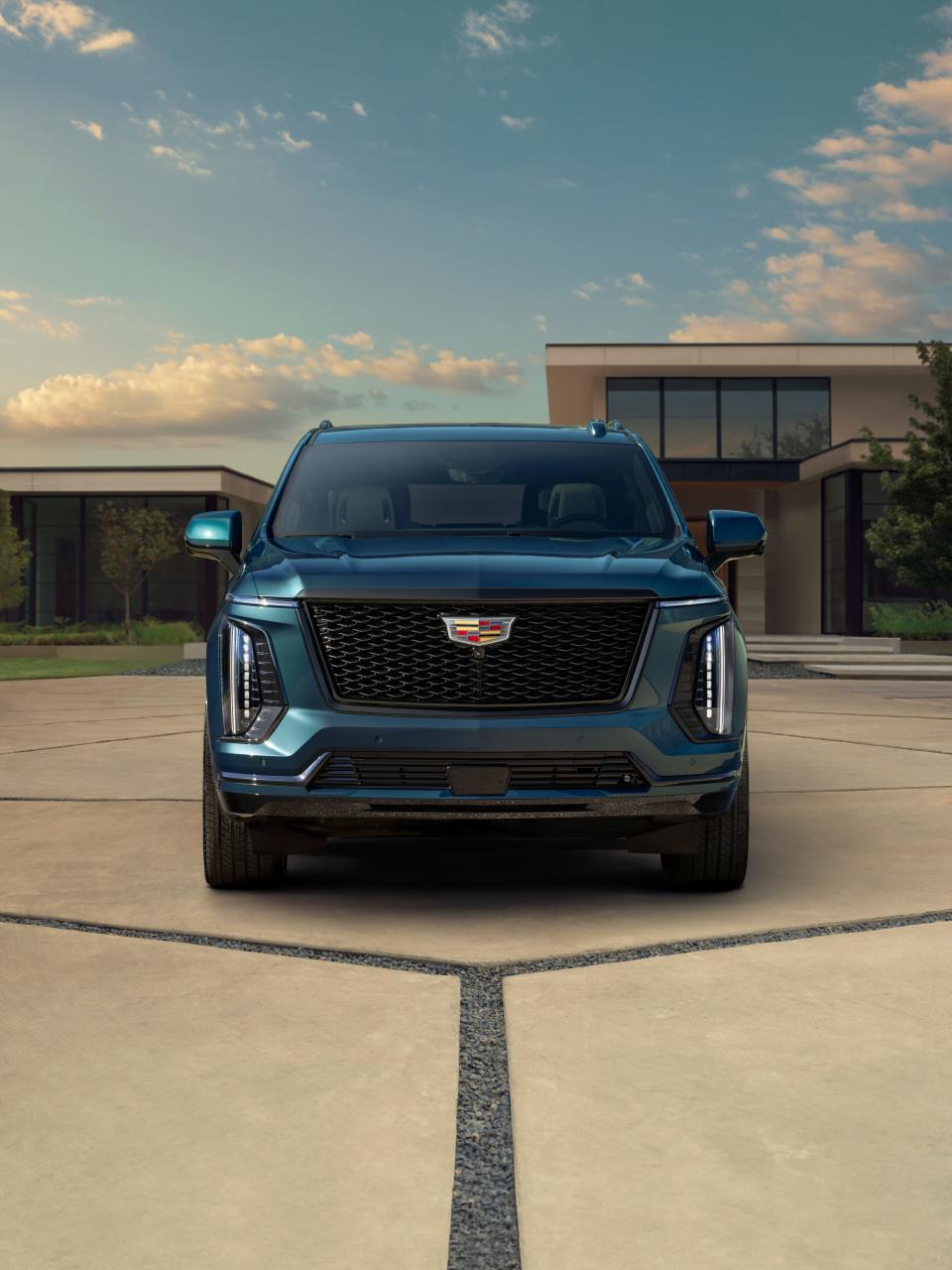 A front-end view of a blue 2025 Cadillac Escalade parked in a driveway.