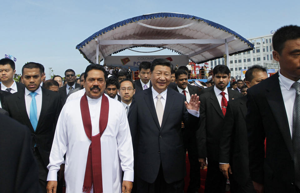 FILE - President Mahinda Rajapaksa, in white, walks with Chinese President Xi Jinping after officially launching a project to construct a $1.4 billion port city being built on an artificial island off Colombo, Sri Lanka, Wednesday, Sept. 17, 2014. China says its initiative to build ports and other infrastructure across Asia and Africa, paid for with Chinese loans, will boost trade. (AP Photo/Eranga Jayawardena, File)