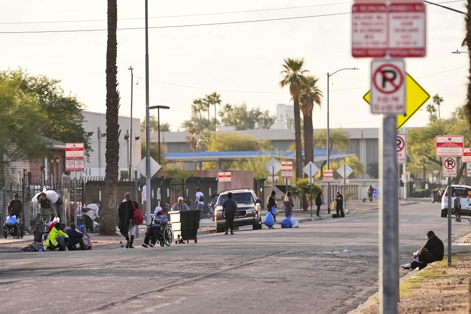 Homeless people gather where the homeless camp called "The Zone" used to encompass, Tuesday, Dec 19, 2023, in Phoenix. Roosevelt White III, who was 36 when he died of a stroke in September after falling ill in the Phoenix homeless encampment known as "The Zone" is among thousands of homeless people who died this year and are being remembered at winter solstice events for Homeless Persons' Memorial Day. (AP Photo/Matt York)