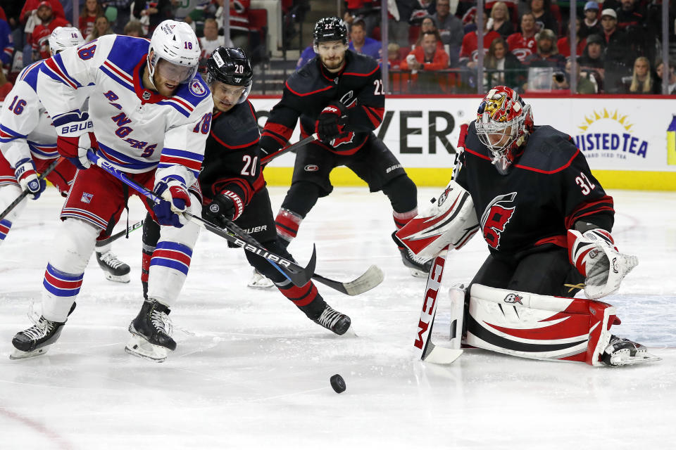 New York Rangers' Andrew Copp (18) battles for the puck with Carolina Hurricanes' Sebastian Aho (20) in front of Hurricanes goaltender Antti Raanta (32) with Hurricanes Brett Pesce (22) nearby during the first period of Game 7 of an NHL hockey Stanley Cup second-round playoff series in Raleigh, N.C., Monday, May 30, 2022. (AP Photo/Karl B DeBlaker)