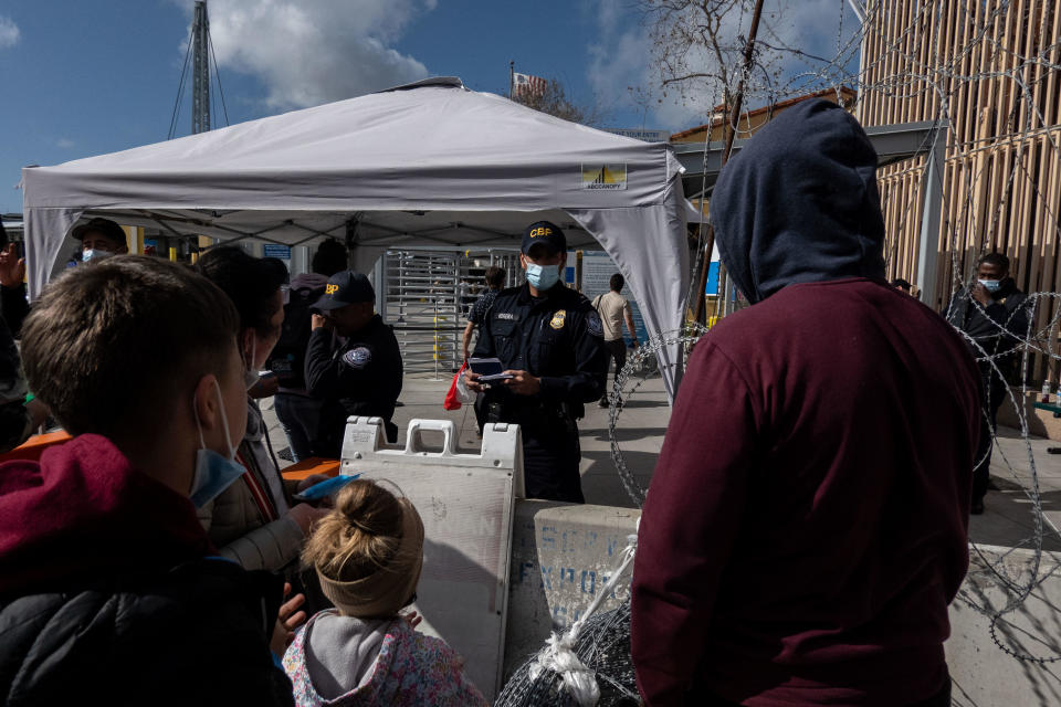 U.S. Customs and Border Protection agents check the passports of Ukrainian refugees looking to cross into the U.S. at the San Ysidro Port of Entry border crossing bridge in Tijuana, Mexico, on Sunday, March 20, 2022. / Credit: Bloomberg