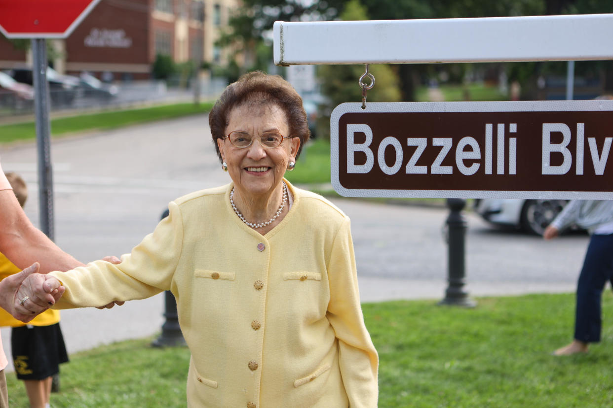 Madeline Bozzelli stands next to the sign that temporarily renamed Broad Boulevard in Cuyahoga Falls in her and her husband's honor in 2020.