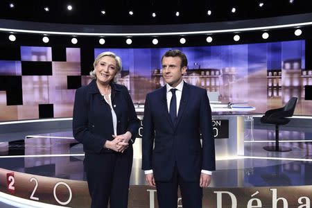 Candidates for the 2017 presidential election, Emmanuel Macron (R), head of the political movement En Marche !, or Onwards !, and Marine Le Pen, of the French National Front (FN) party, pose prior to the start of a live prime-time debate in the studios of French television station France 2, and French private station TF1 in La Plaine-Saint-Denis, near Paris, France, May 3, 2017. REUTERS/Eric Feferberg/Pool