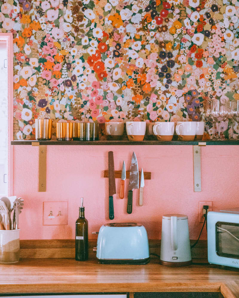 Glassware on open shelf in pink and floral kitchen
