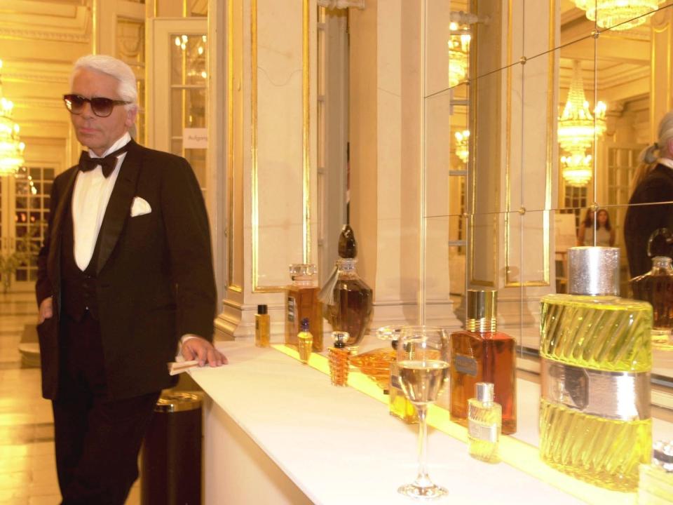 Karl Lagerfeld standing near perfume bottles in mirrored room