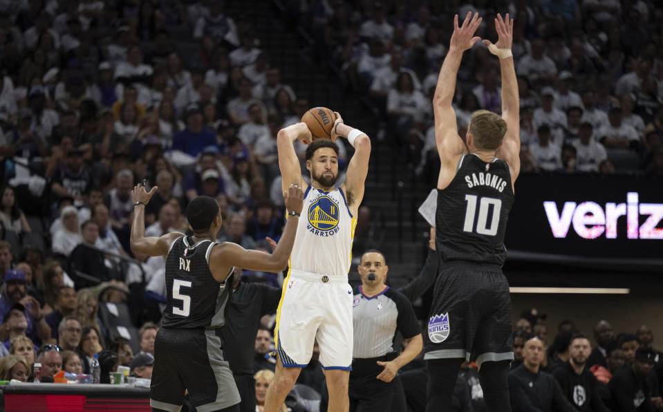 Sacramento Kings guard De'Aaron Fox (5) and forward Domantas Sabonis (10) defend against Golden State Warriors guard Klay Thompson (11) who looks to pass during the second half of Game 7 of an NBA basketball first-round playoff series Sunday, April 30, 2023, in Sacramento, Calif. (AP Photo/José Luis Villegas)