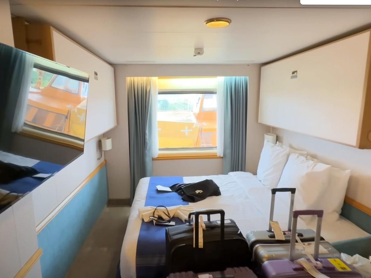 cruise cabin with bed, TV, luggage on Villa Vie Odyssey