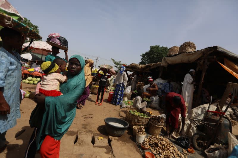 A man puts ginger plant bulbs in buckets at a market in Kaduna