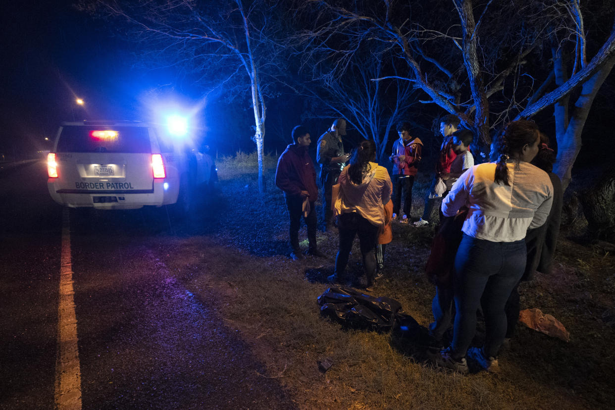 An immigration official stops a group of migrants from Central America as they walk on a road after they crossed the Texas-Mexico border, Friday, May 12, 2023, in Fronton, Texas. (AP Photo/Julio Cortez)