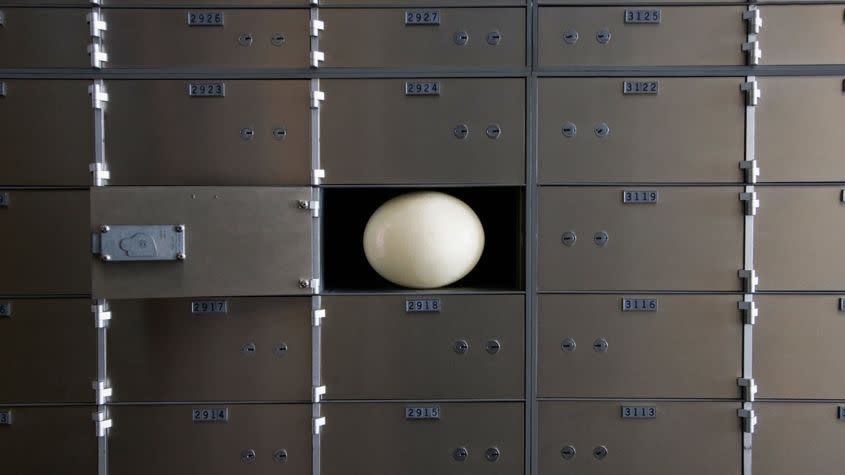 An open safe deposit box with an egg in it.