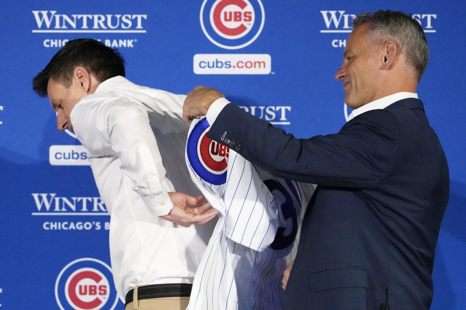 Chicago Cubs president of baseball operations Jed Hoyer, right, helps new manager Craig Counsell put on a Cubs jersey during an introductory press conference in Chicago, Monday, Nov. 13, 2023. (AP Photo/Nam Y. Huh)