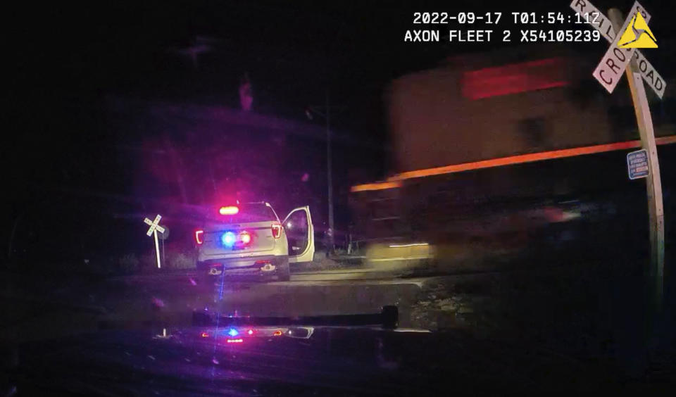 This screen grab from dash camera video provided by the Fort Lupton Police Department shows a freight train barreling toward a parked police car with a suspect inside, Sept. 16, 2022, in Fort Lupton, Colo. A trial began Monday, July 24, 2023, for the police officer accused of putting the handcuffed woman in the car that was hit by the train. The collision seriously injured 21-year-old Yareni Rios. The date/time stamp shown on the video is incorrect. (Fort Lupton Police Department via AP)