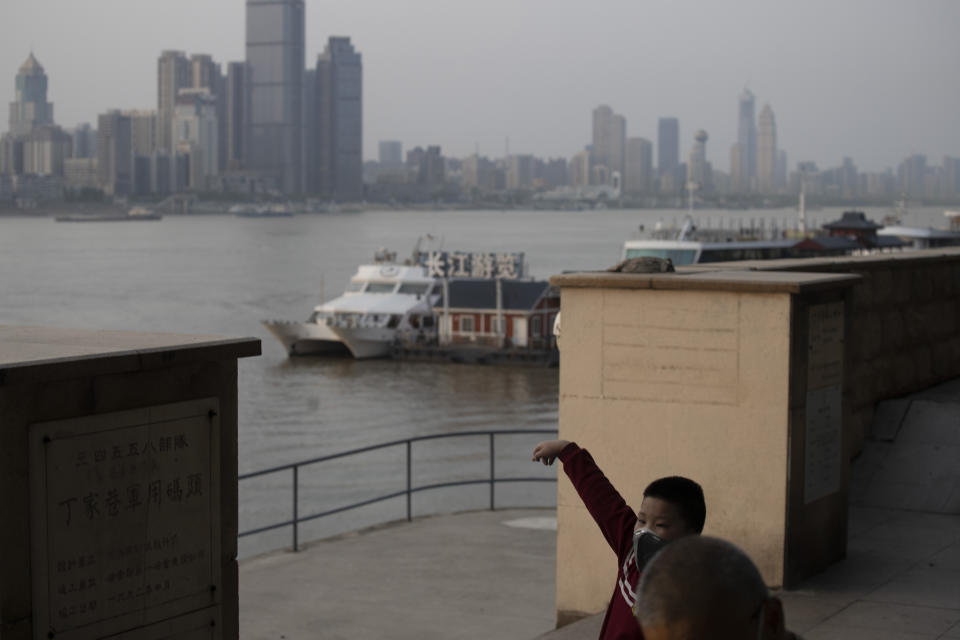 In this April 8, 2020, photo, a child wearing a mask against the coronavirus stretches near a ferry terminal along the Yangtze River in Wuhan in central China's Hubei province. The reopening of ferry service on the Yangtze River, the heart of life in Wuhan for more than 20 centuries, was an important symbolic step in official efforts to get business and daily life in this central Chinese city of 11 million people back to normal after a 76-day quarantine ended in the city at the center of the coronavirus pandemic. (AP Photo/Ng Han Guan)