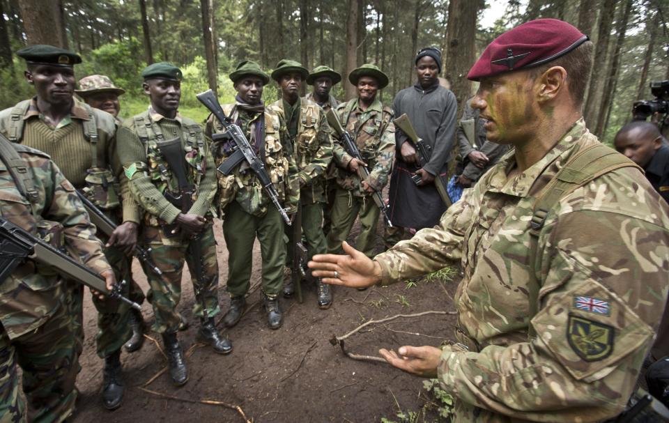 FILE - In this Thursday, Dec. 5, 2013 file photo, Corporal Andrew Smith of Britain's 3rd Battalion, The Parachute Regiment, right, instructs rangers of the Kenya Wildlife Service and Kenya Forest Service about the use of hand signals while patrolling, as they stage a demonstration of the skills they have learned over the last few days of joint anti-poaching training, in the forest near Nanyuki, Kenya. Africa is getting tougher in its fight against poaching with new laws with stiff penalties, more military training for rangers, and new technology like drones with thermal cameras are all helping to protect rhinos and elephants. (AP Photo/Ben Curtis, File)