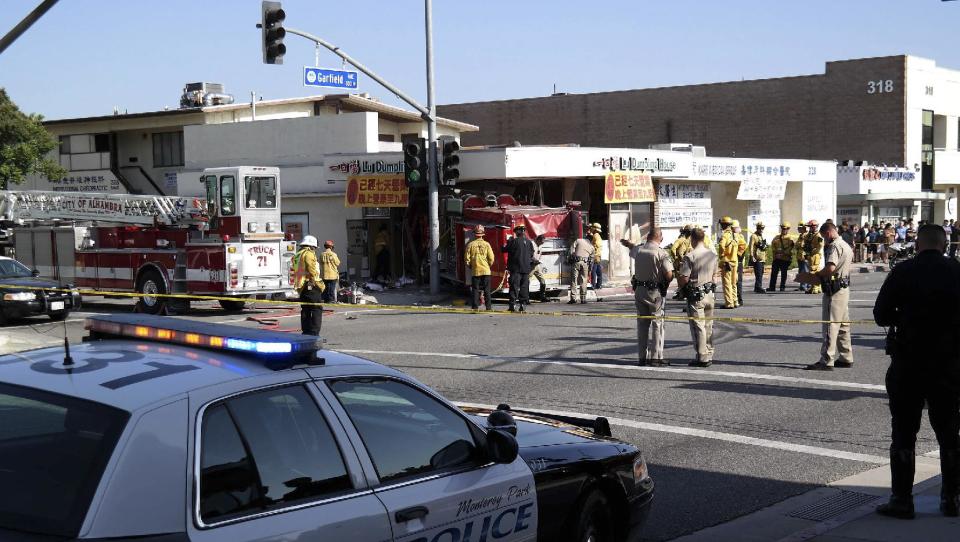 Firefighters and other officials work the scene of an accident where two firetrucks answering a call collided en route to a fire Wednesday, April 16, 2014, in Monterrey Park, Calif. The collision sent one firetruck careening into a restaurant, leaving 14 people, including several firefighters, injured. (AP Photo/Nick Ut)