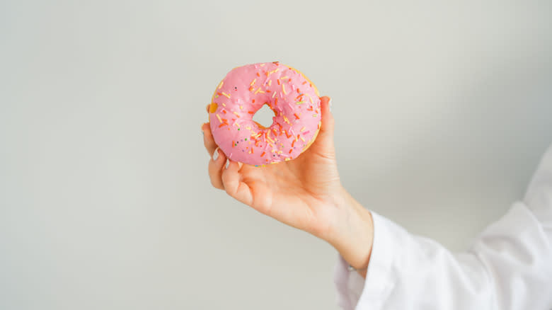 hand holding pink donut