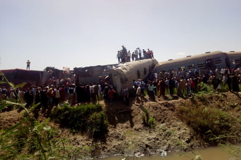 People inspect the damage after two trains have collided near the city of Sohag