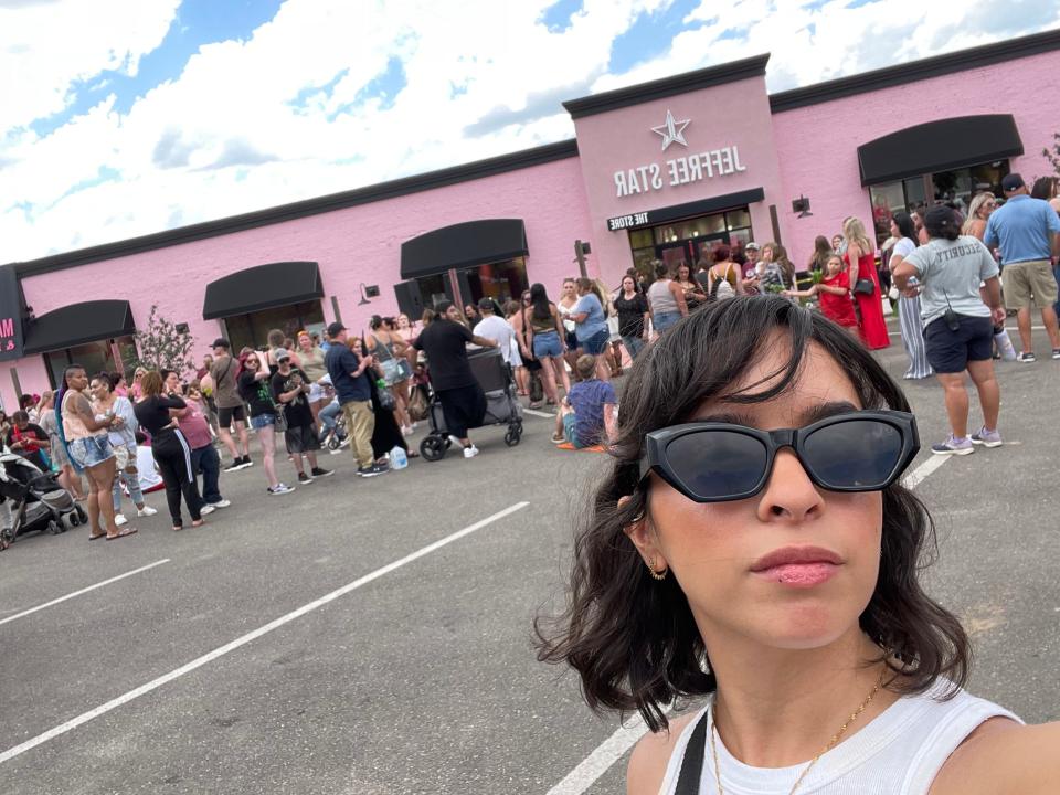 woman in sunglasses posing in front of crowds lined up in front of Jeffree Star store