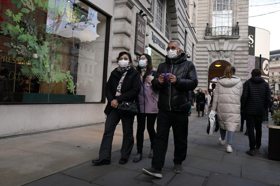 People wear masks as they walk in Regent Street, in London, Saturday, Dec. 4, 2021. Britain says it will offer all adults a booster dose of vaccine within two months to bolster the nation's immunity as the new omicron variant of the coronavirus spreads. New measures to combat variant came into force in England on Tuesday, with face coverings again compulsory in shops and on public transport. (AP Photo/Alberto Pezzali)